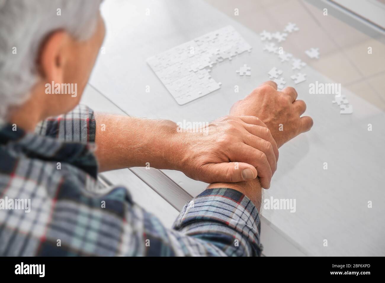 Senior man with Parkinson syndrome doing puzzle at home Stock Photo Alamy