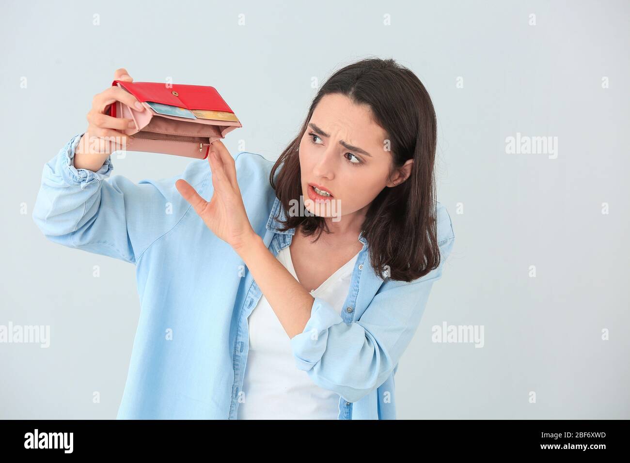 Scared Empty Wallet Worried young woman with empty wallet on light background Stock Photo ...