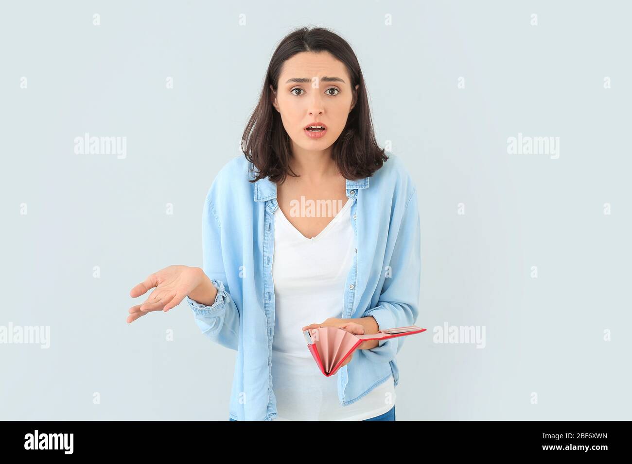 Scared Empty Wallet Worried young woman with empty wallet on light background Stock Photo ...