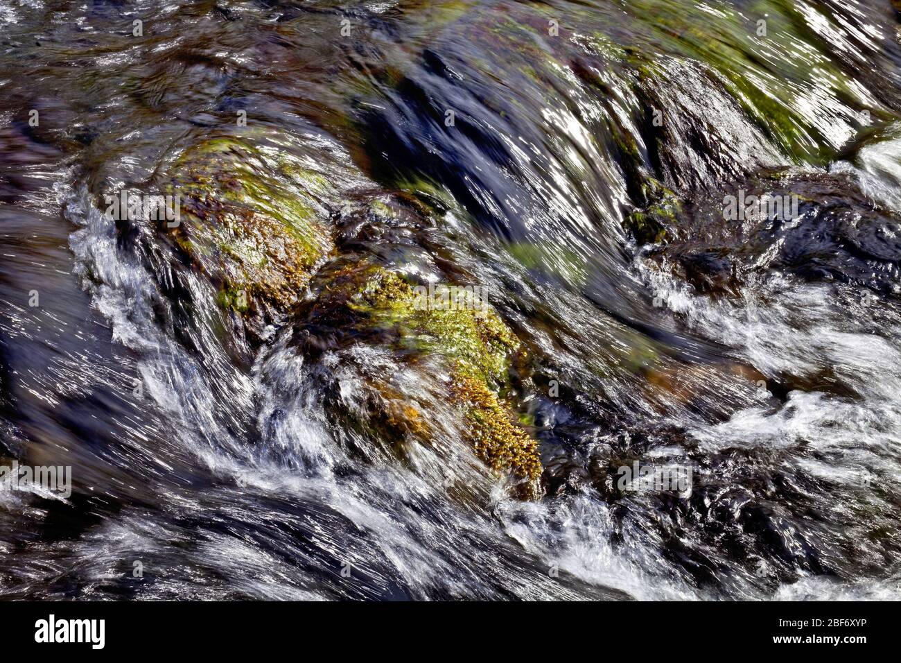 running water with sun reflections showing the streaming direction of the water, Iceland, East Iceland, Stora Sandfell Stock Photo