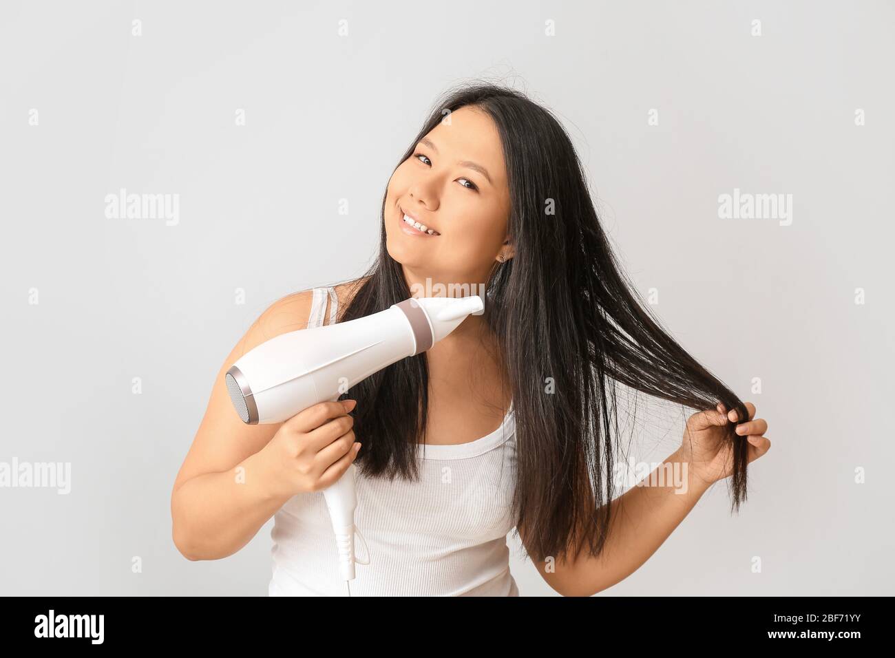 Beautiful Asian Woman With Hair Dryer On Light Background Stock Photo Alamy