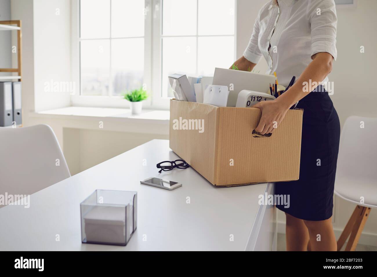Unemployment Dismissed businesswoman upset with a cardboard box leaves the workplace from the office of the company. Stock Photo
