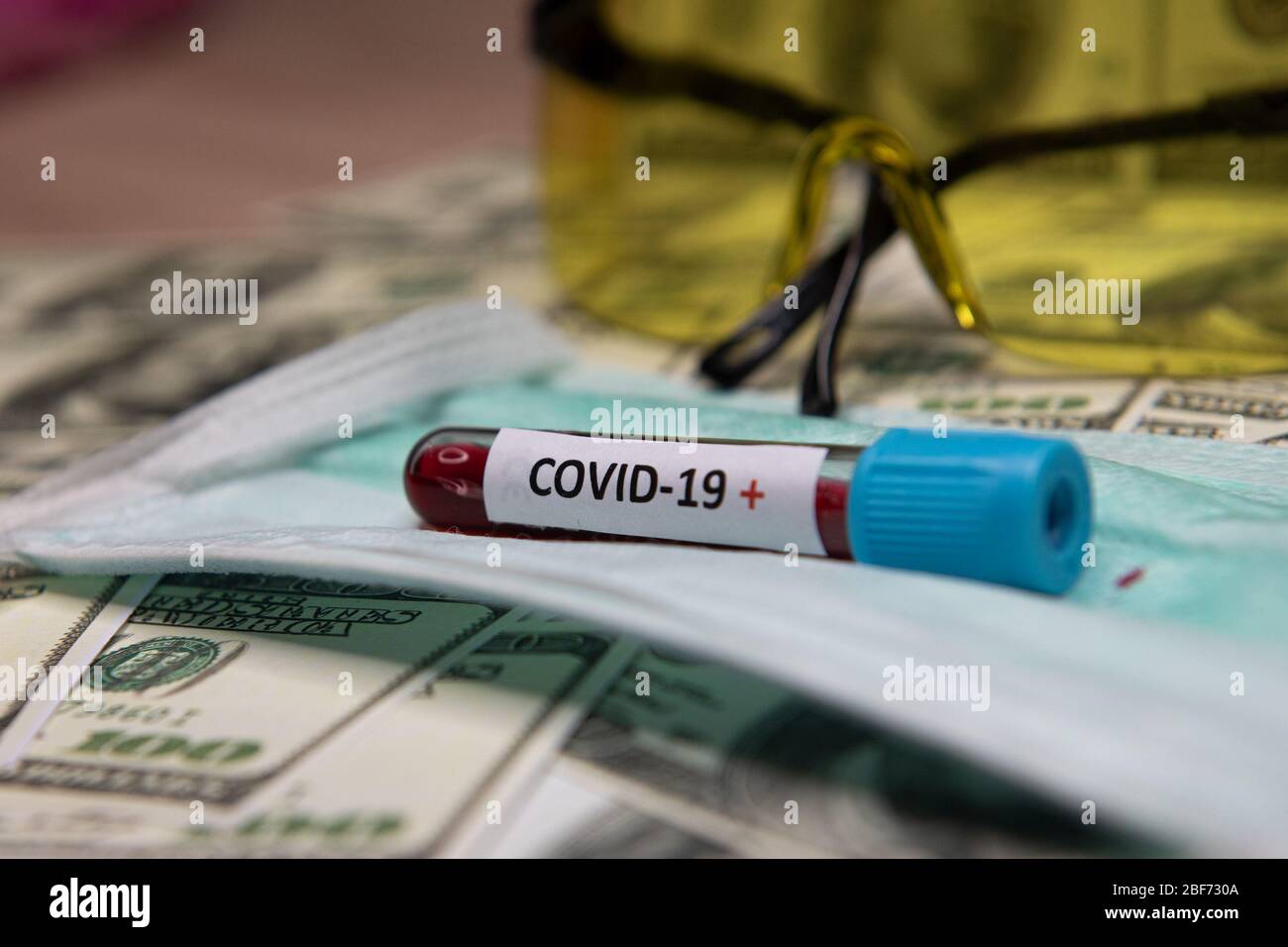 Dollars money and tube with blood and positive test at covid-19. Stock Photo