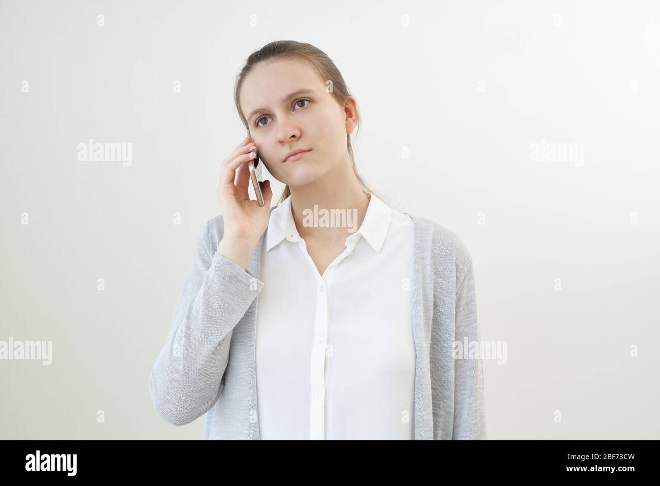 Calm, unemotional woman talks on phone, listens to other person, does not react. Stock Photo
