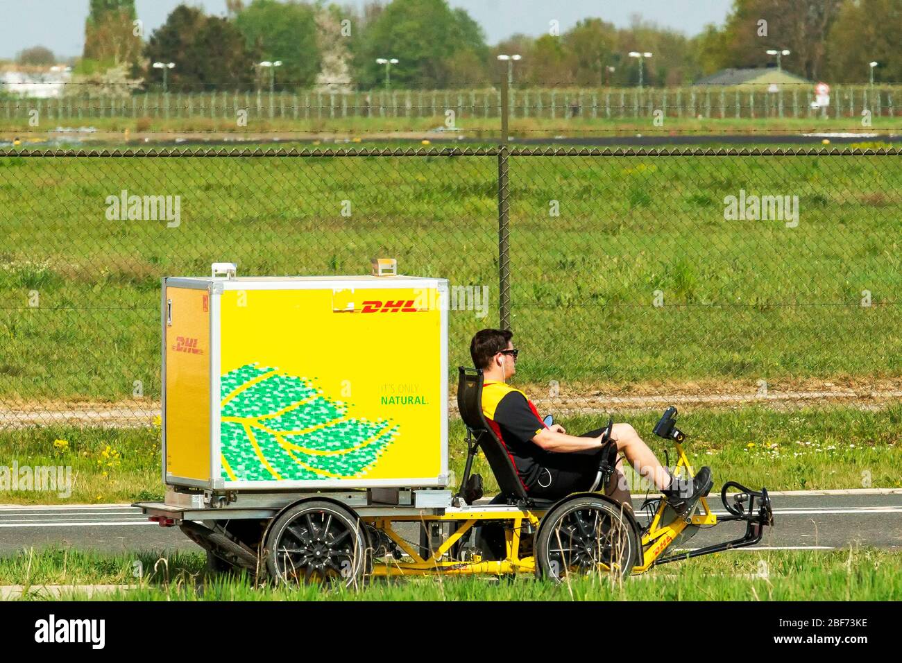 16 april 2020 Maastricht, The Netherlands Airplanes leaving the Airport DHL pakketbezorger met ligfiets en bagagebak  DHL parcel delivery with recumbent bike and luggage compartment Stock Photo
