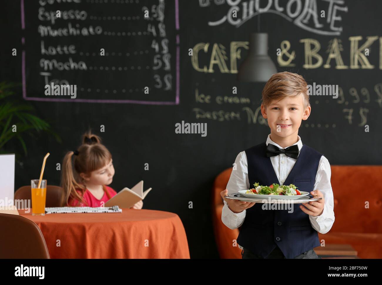 Cute little waiter in restaurant Stock Photo - Alamy