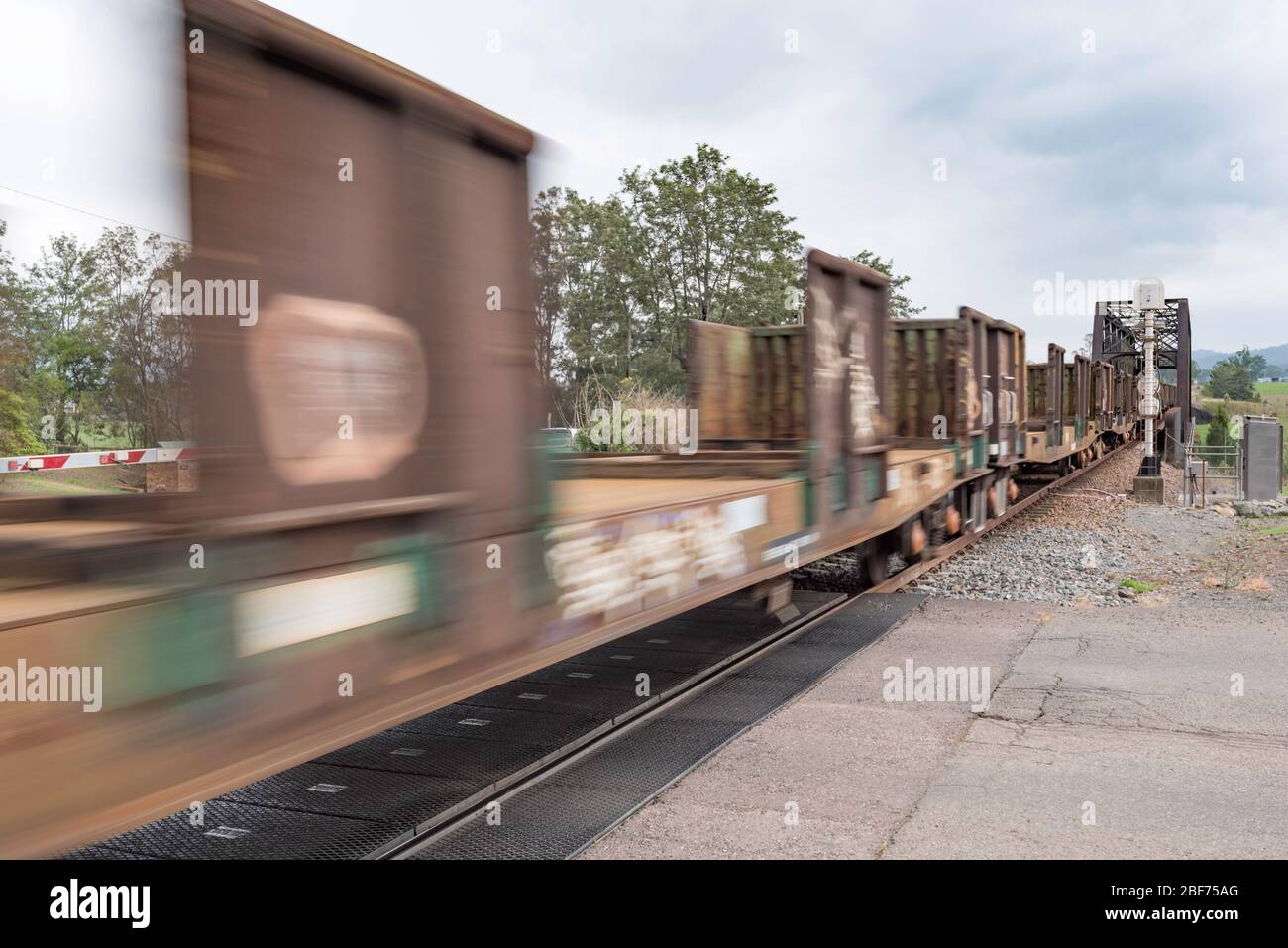 A line of flatbed rail cars being towed by diesel at a