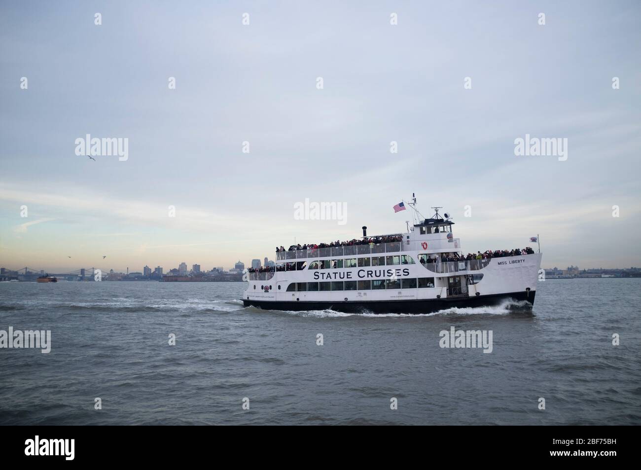 A boat going with tourist to The Statue of Liberty. 'Statue Cruises'. Full of tourists on a cloudy day. Stock Photo