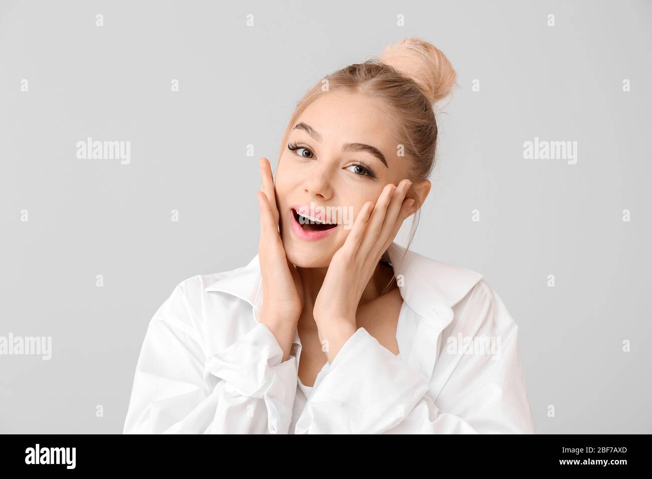 Surprised young woman on grey background Stock Photo - Alamy