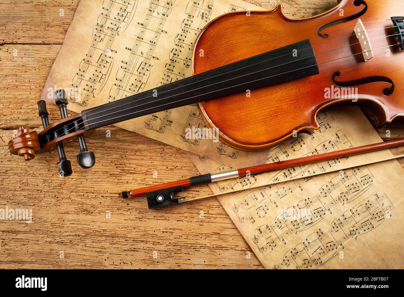 classic retro violin music string instrumt with old music note sheet paper on old oak wood wooden background. classical musical romantic valentines da Stock Photo