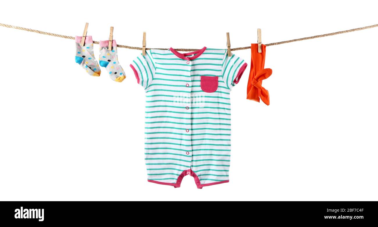 Baby clothes and accessories hanging on rope against white background ...