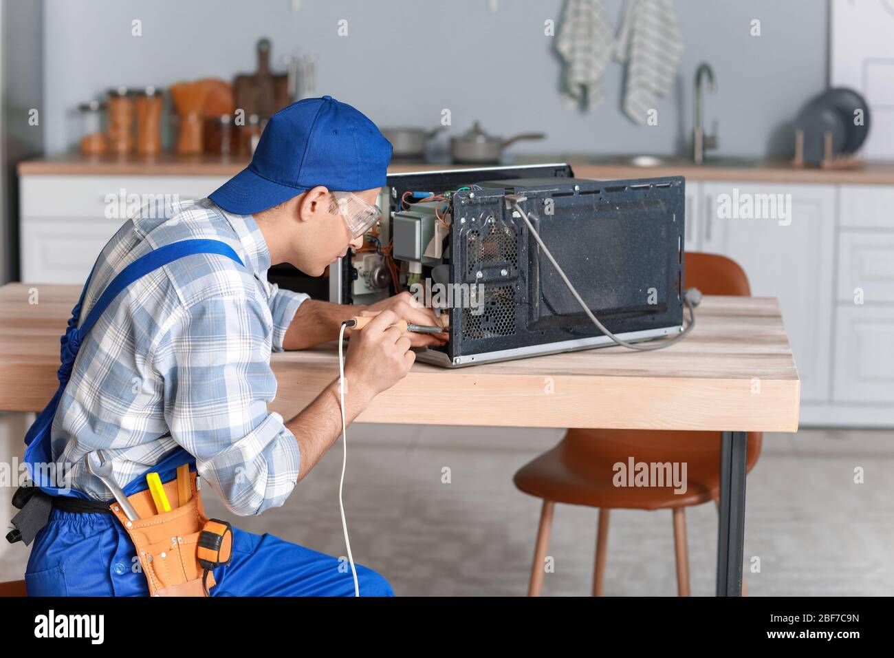 Worker repairing microwave oven in kitchen Stock Photo