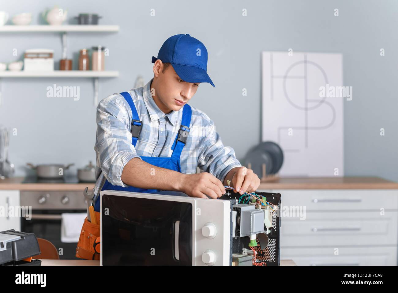 Worker repairing microwave oven in kitchen Stock Photo