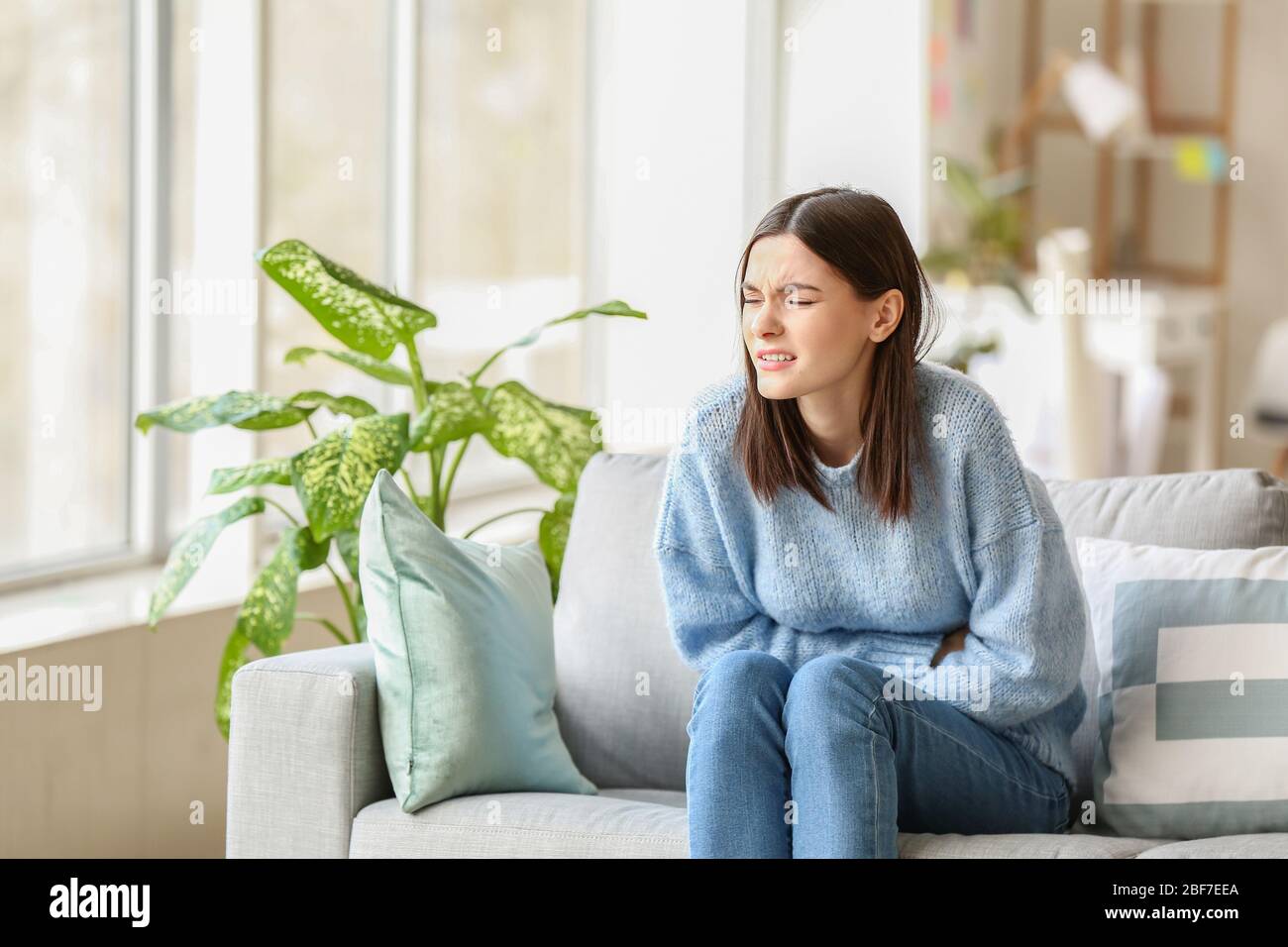 Young woman suffering from menstrual cramps at home Stock Photo - Alamy, image size:1300x956