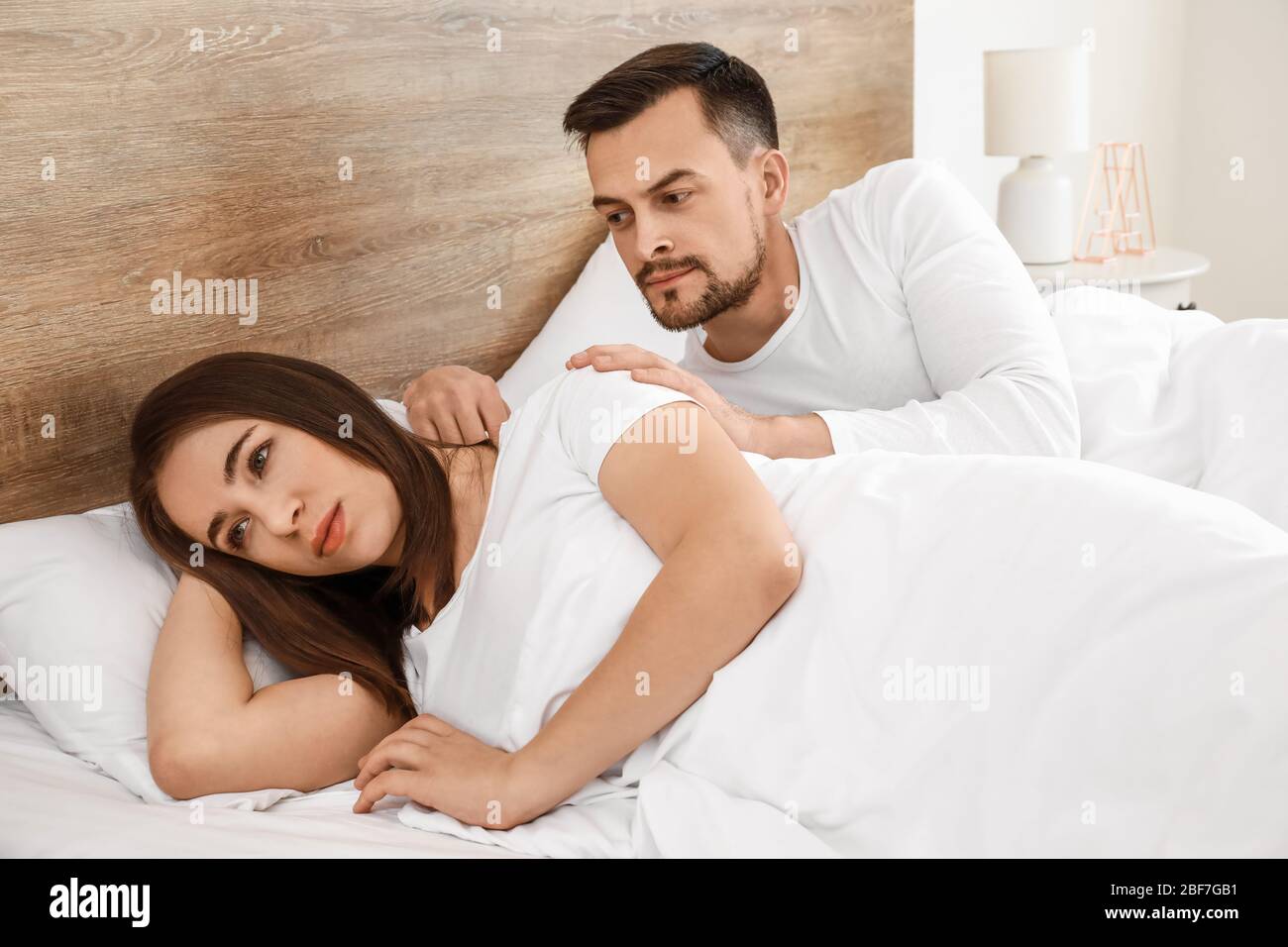 Young man trying to make peace with wife after quarrel in bedroom Stock Photo photo