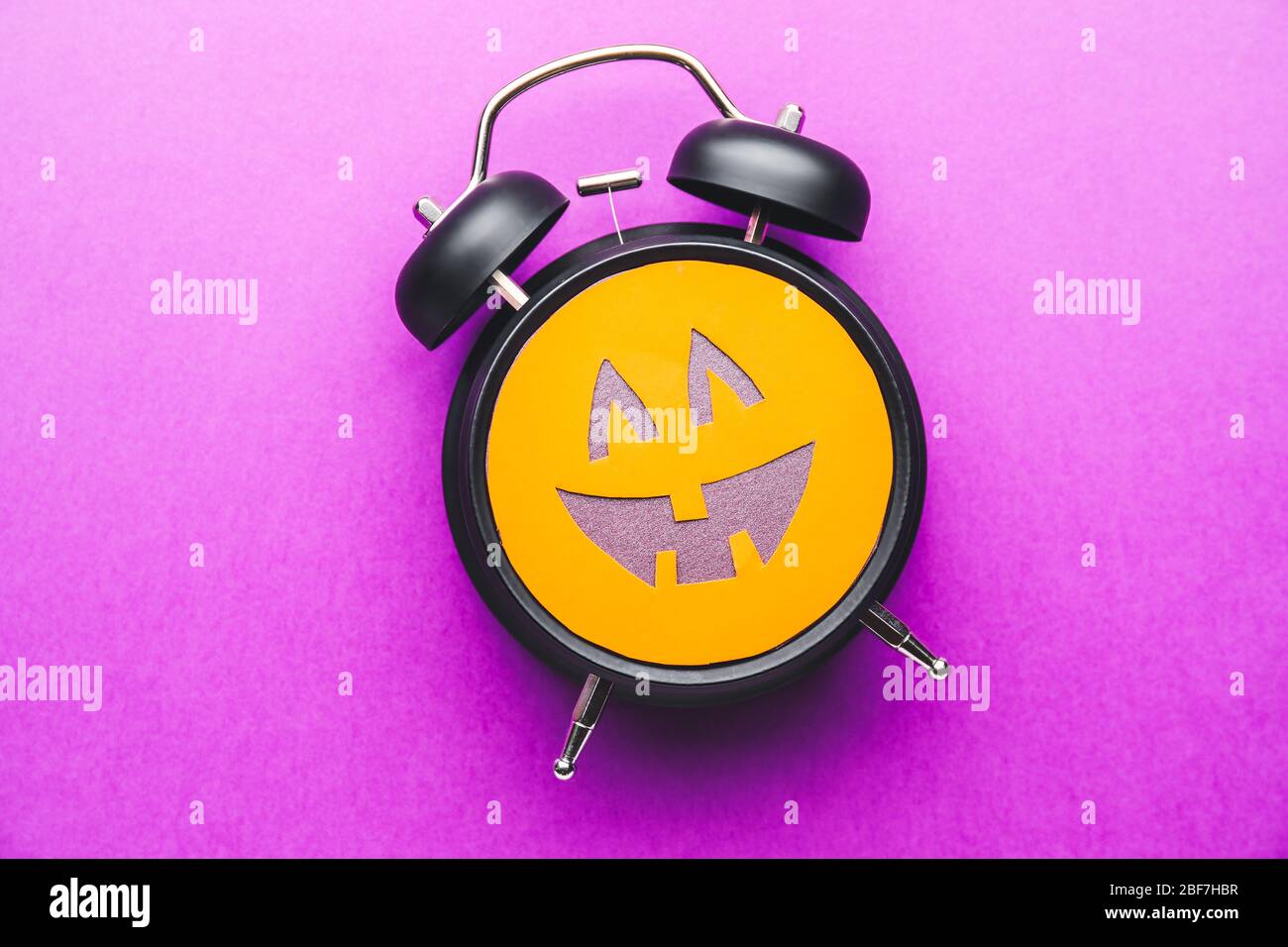 Alarm clock with scary face on color background. Halloween celebration