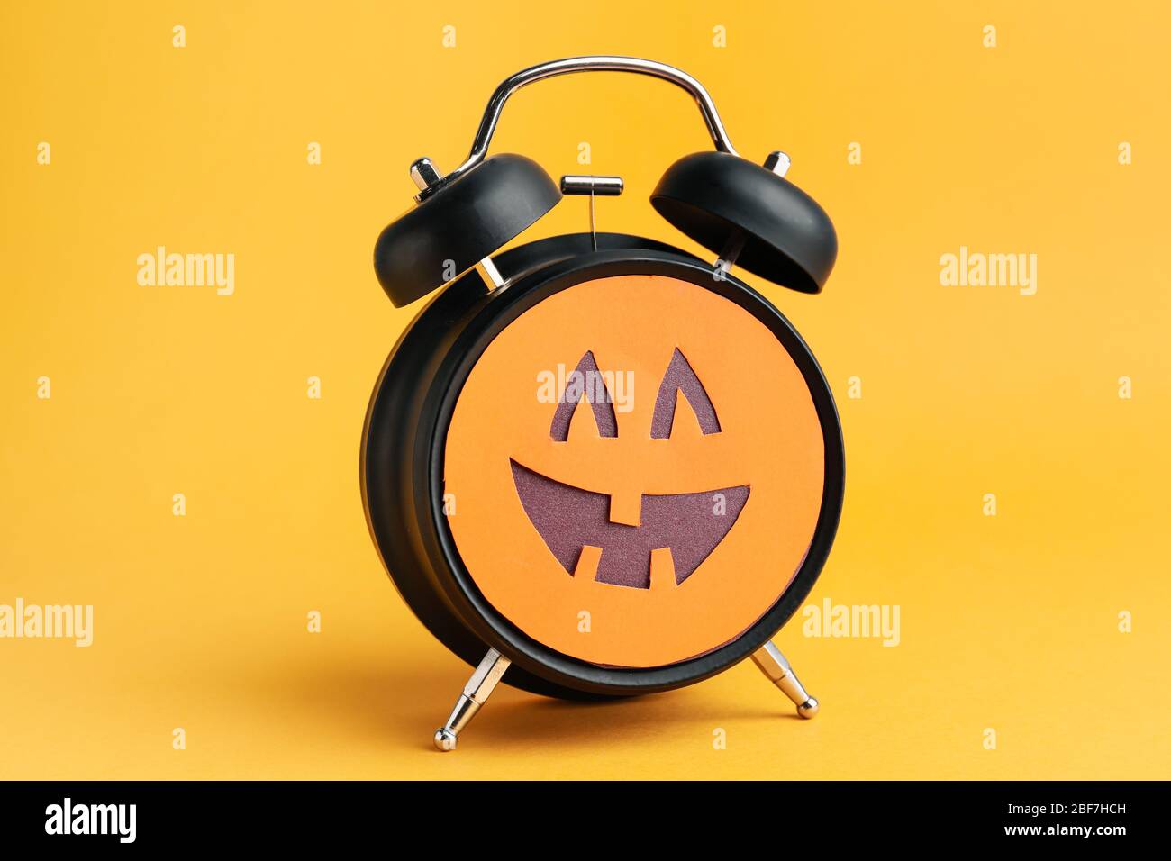 Alarm clock with scary face on color background. Halloween celebration