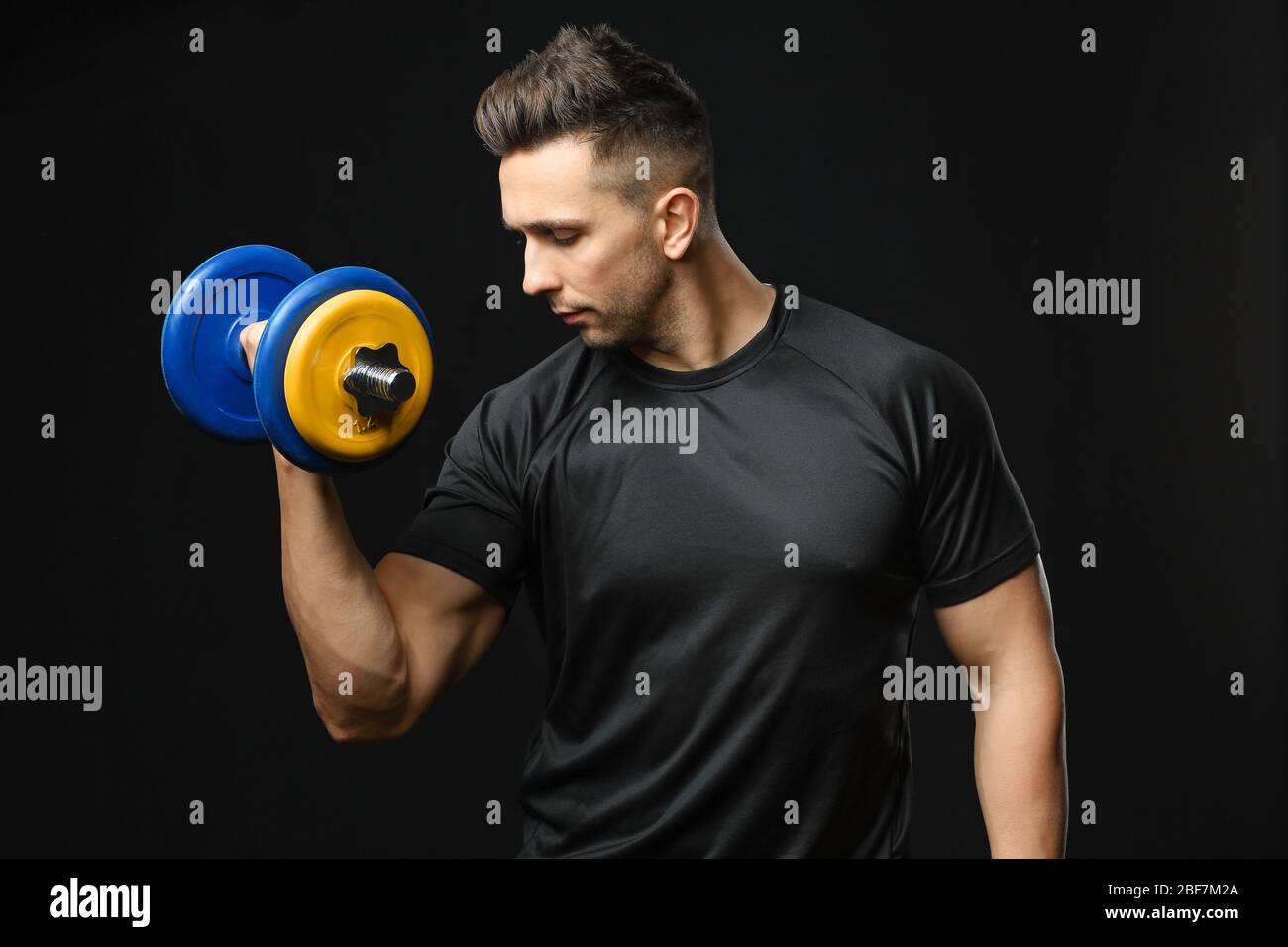 Sporty man with dumbbell on dark background Stock Photo
