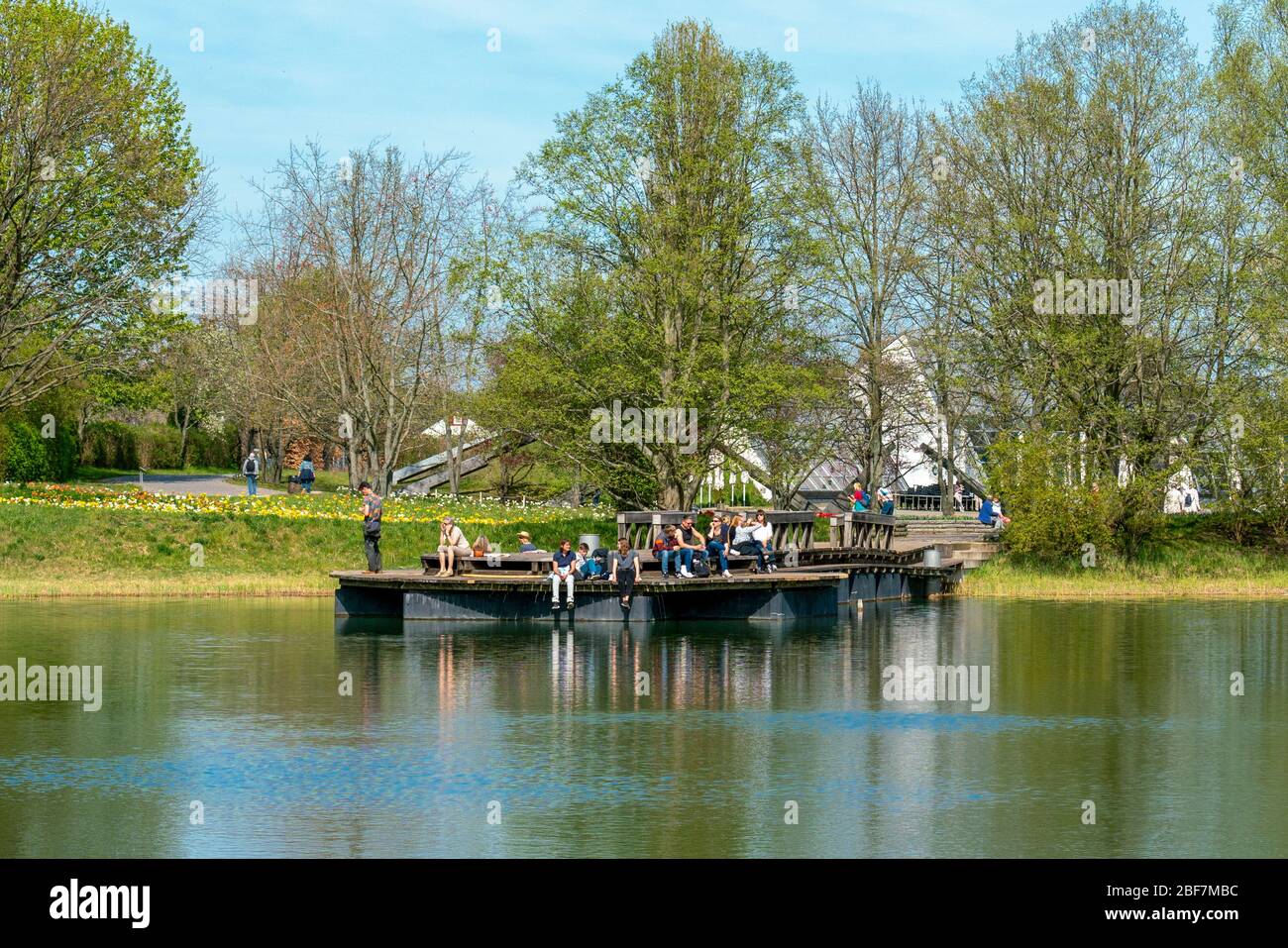 Britzer Garten, Berlin, Germany - april 16, 2020: visitors enjoying the sunshine on the lake platform Stock Photo