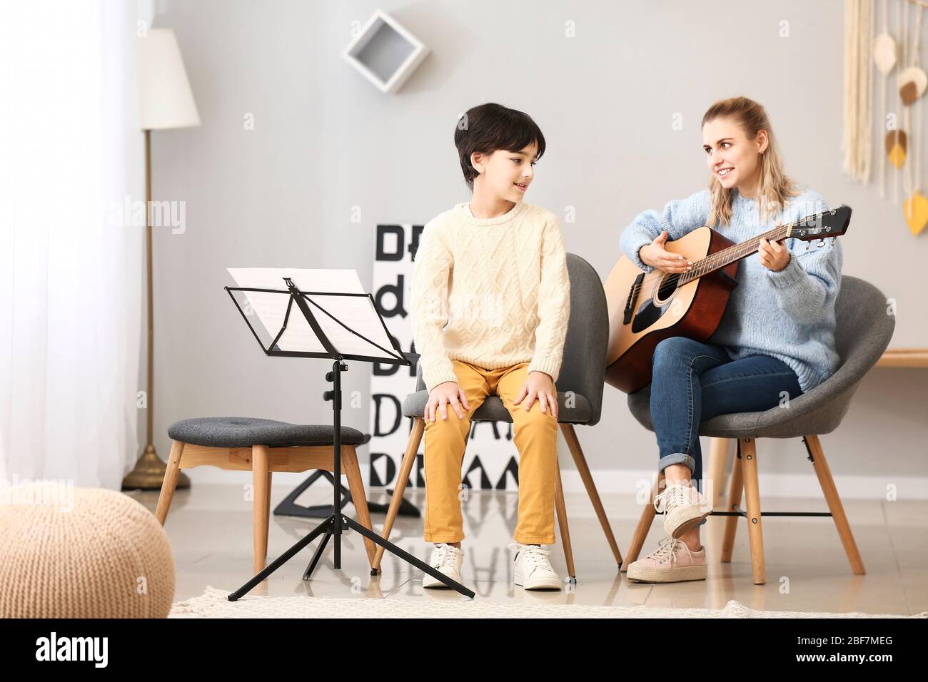 Private music teacher giving guitar lessons to little boy at home Stock ...