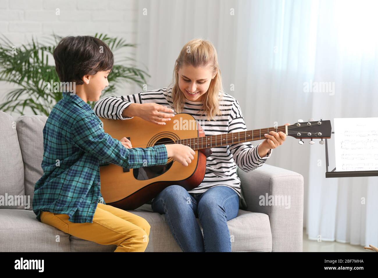 Private music teacher giving guitar lessons to little boy at home Stock ...