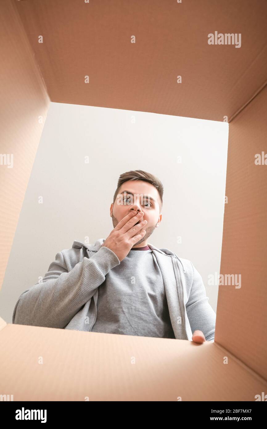 Shocked man with open box, view from inside Stock Photo