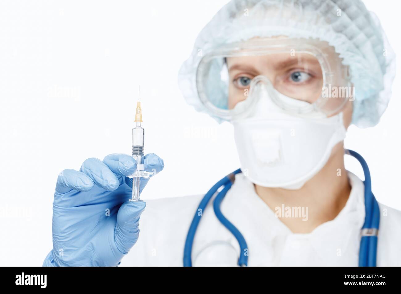 Close-up shot of doctor wearing protective suit, goggles and surgical mask holding syringe ready for injection Stock Photo