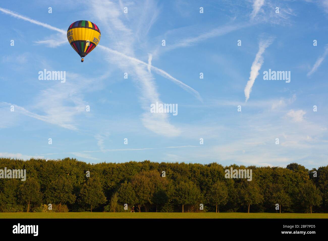 A hot air balloon in a blue sky with crossing clouds Stock Photo - Alamy