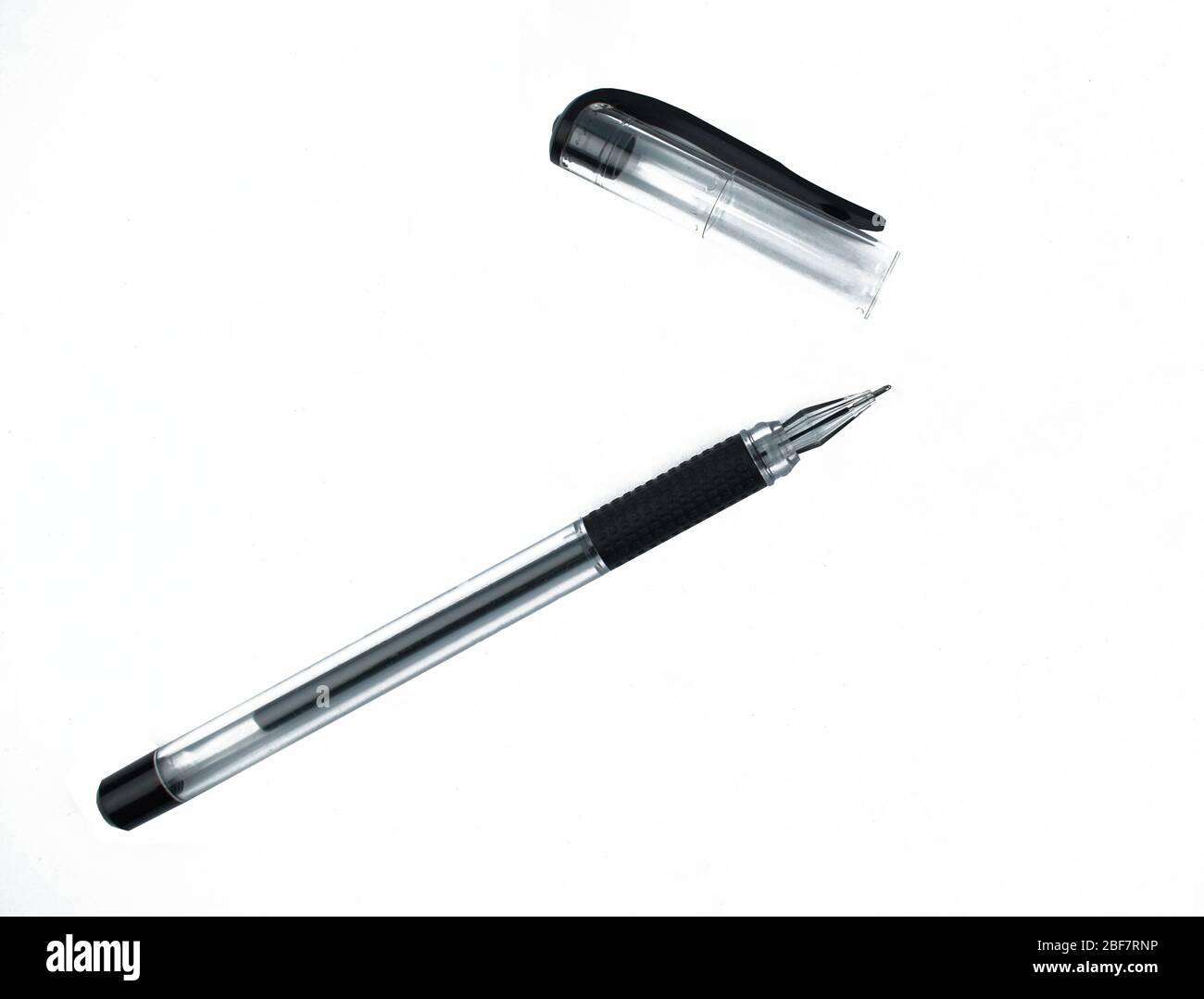 Black colored ball point pen and its cap scattered on top of a white isolated background Stock Photo