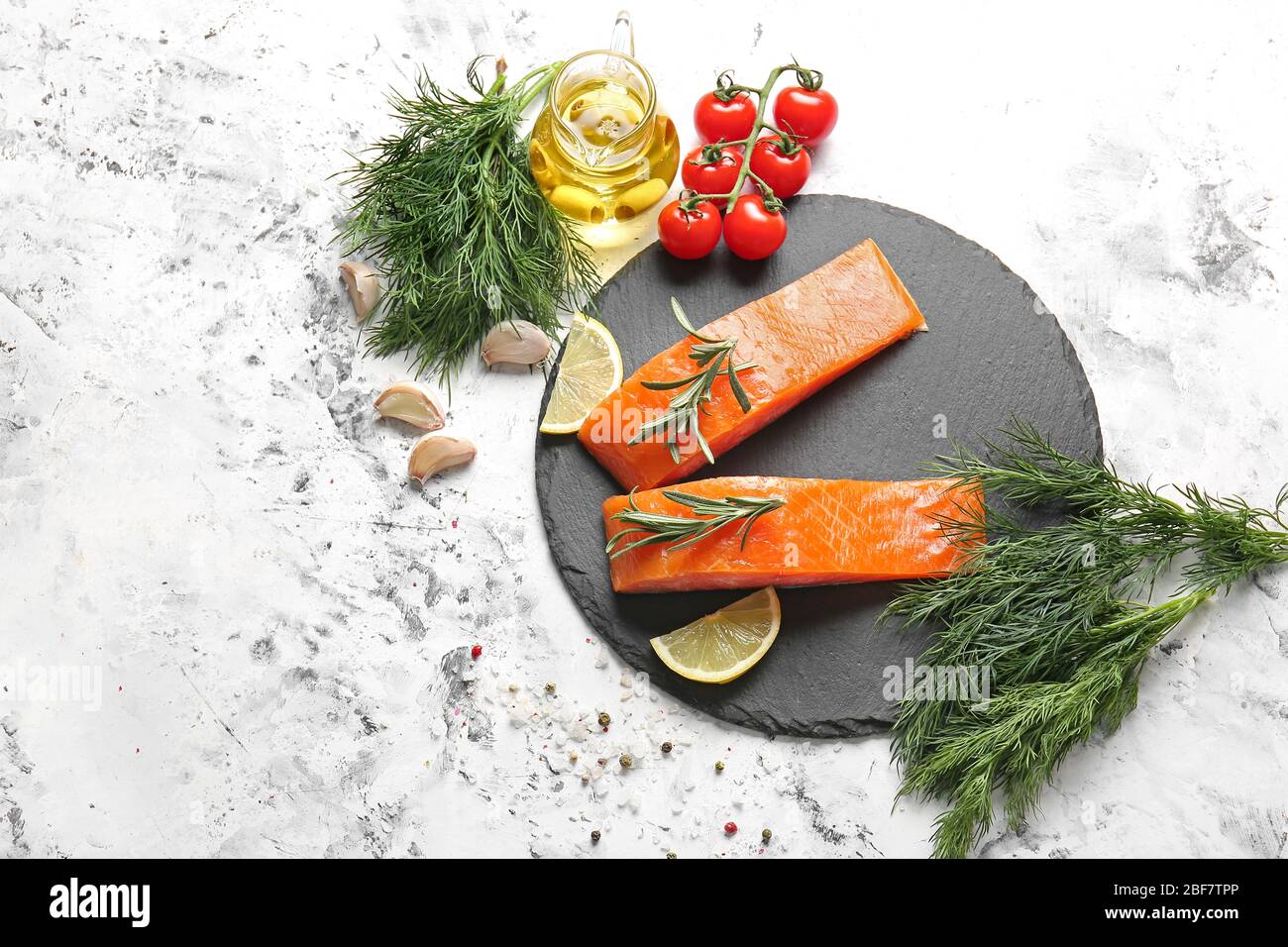 Raw salmon fillet with herbs, lemon, garlic and oil on white background ...