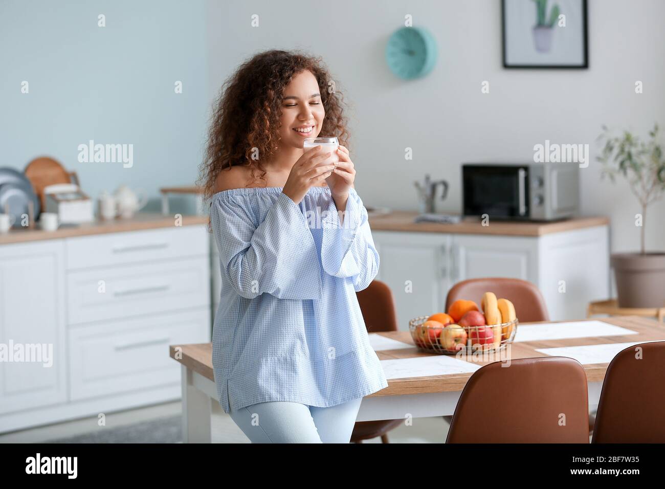 Young woman drinking tasty yogurt in kitchen Stock Photo Alamy