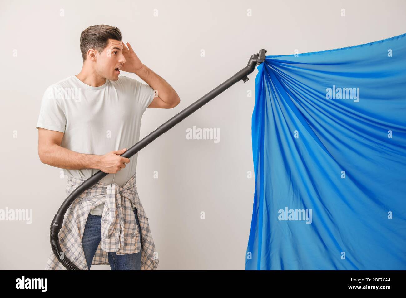 Afraid Young Man With Sucked Into Vacuum Cleaner Curtain Against
