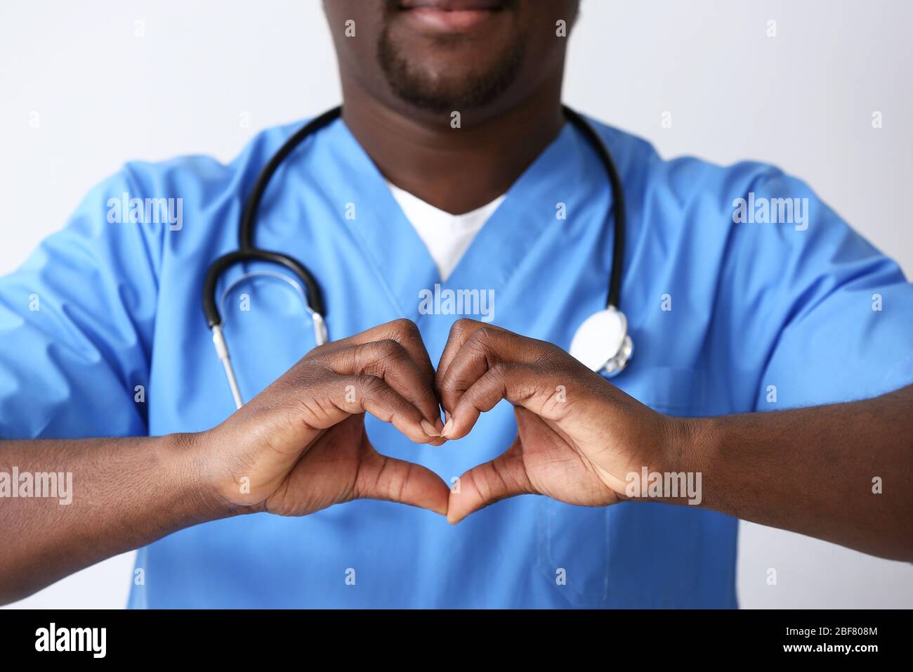 Male African-American nurse making heart with his hands on light ...
