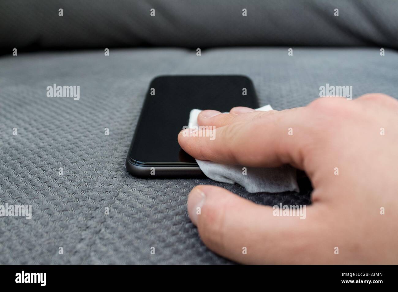 Man's hand cleaning smartphone screen with disinfectant spray