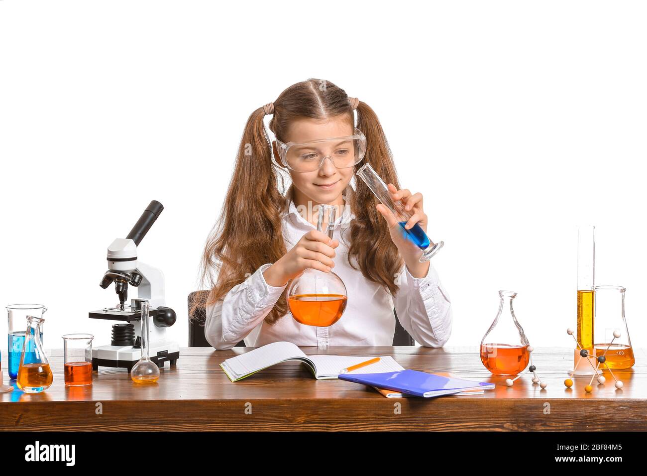 Cute little girl studying chemistry at table against white background Stock  Photo - Alamy