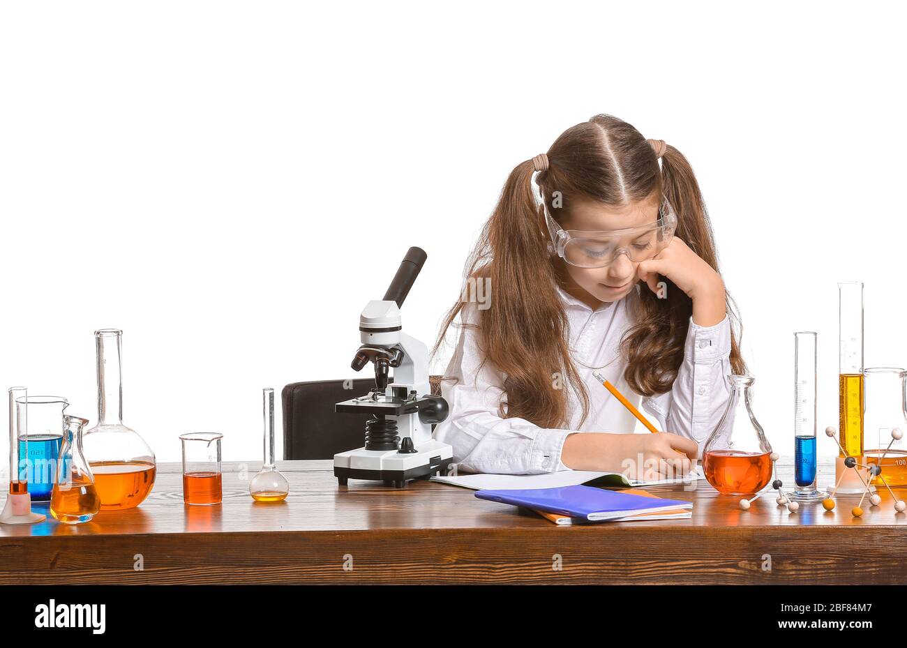 Cute little girl studying chemistry at table against white background Stock  Photo - Alamy
