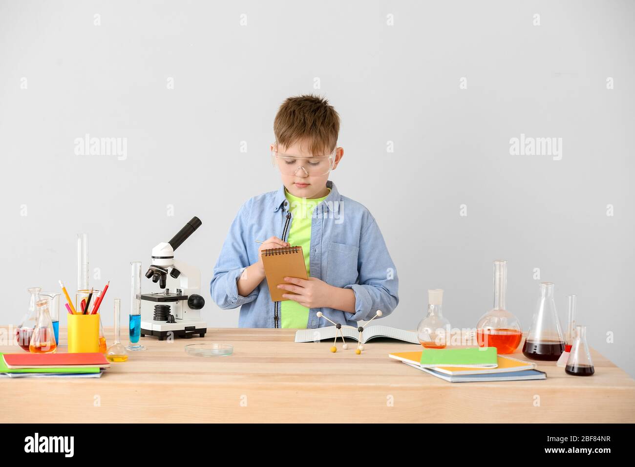 Cute little boy studying chemistry at table against grey background Stock  Photo - Alamy