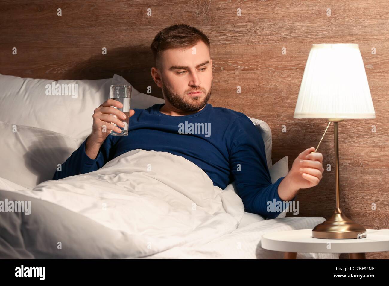 Young man drinking water in bedroom at night Stock Photo Alamy