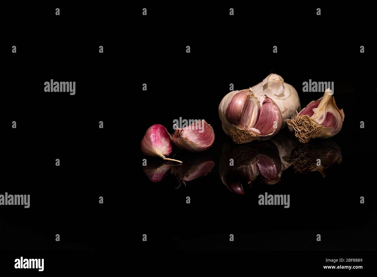 Garlic bulb and separated cloves on black background with copy space ...