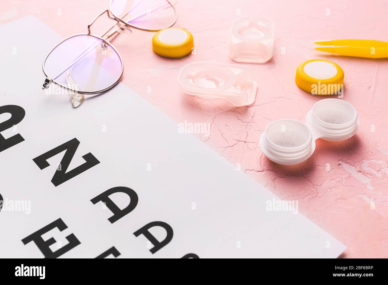 Contact lenses, glasses and eye test chart on color background Stock