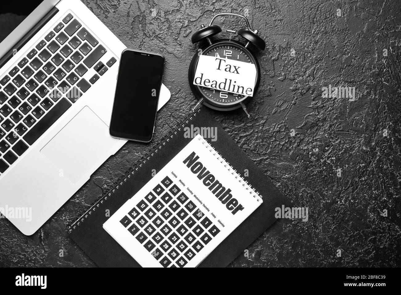 Calendar with alarm clock, laptop, mobile phone and text TAX DEADLINE
