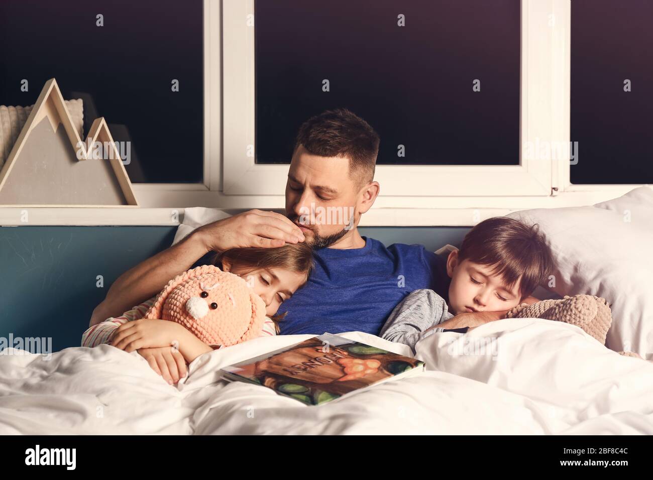 Father and his little sleeping children in bed Stock Photo Alamy