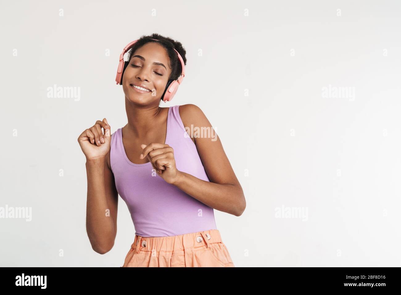 Portrait of african american positive woman using headphones and ...