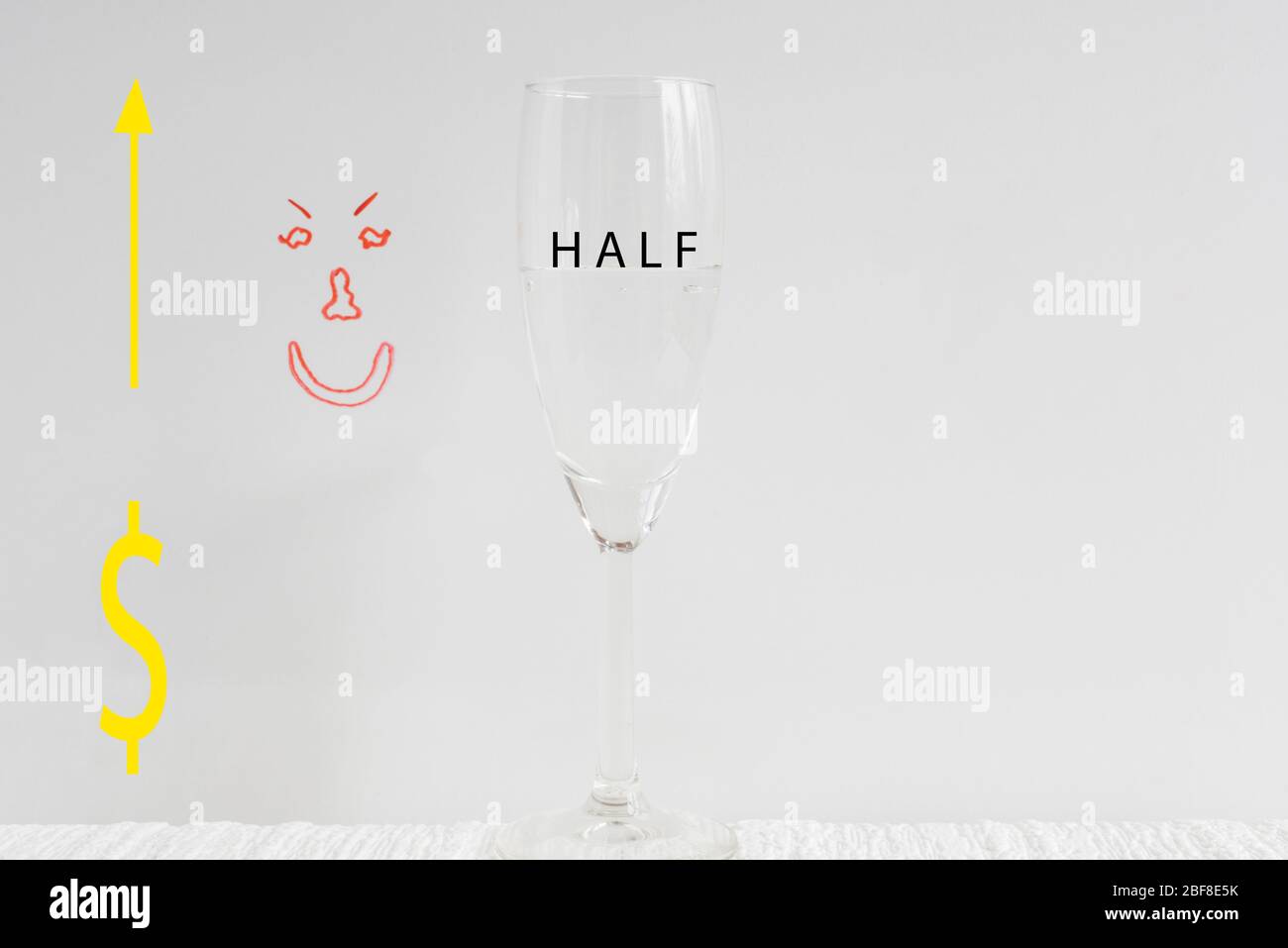 One wine glass, half full with drawn  happy face in background depicting concept of glass half full. Stock Photo