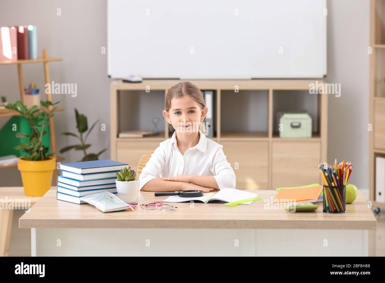 Cute little schoolgirl at desk in classroom Stock Photo - Alamy