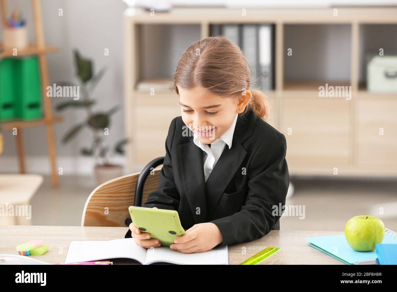 Cute little schoolgirl with calculator at desk in classroom Stock Photo ...
