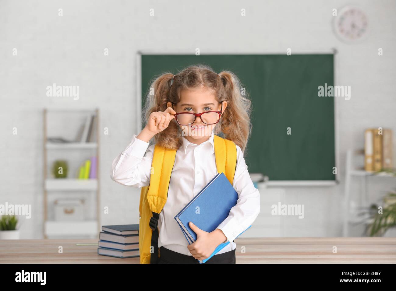 Cute little schoolgirl in classroom Stock Photo - Alamy