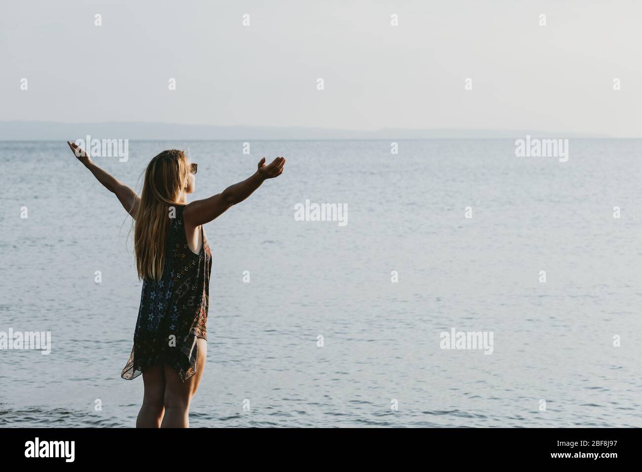 Young woman enjoying sunset by the sea Stock Photo