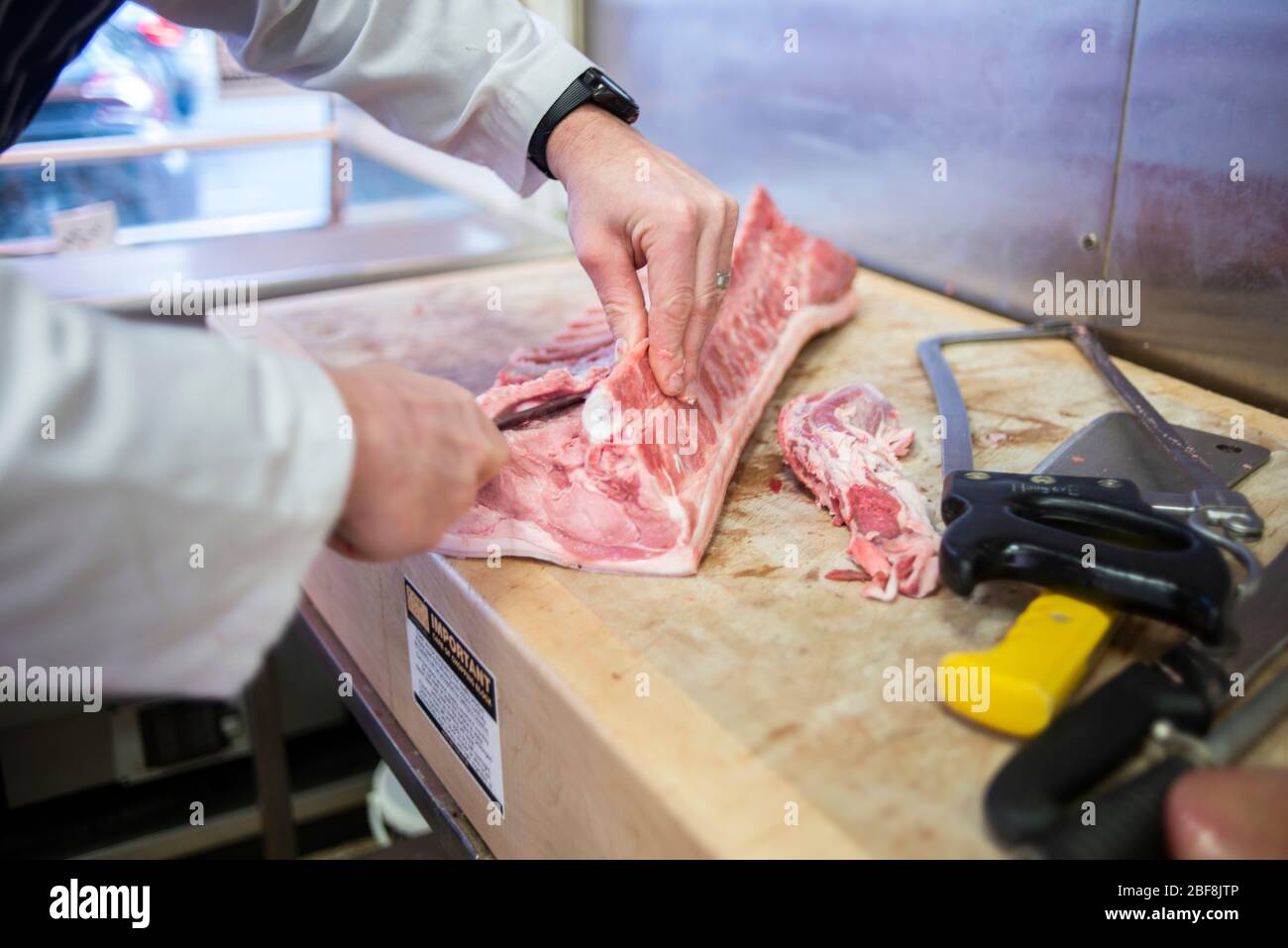 A butcher prepares high-welfarepork to sell in his butchers store Stock Photo