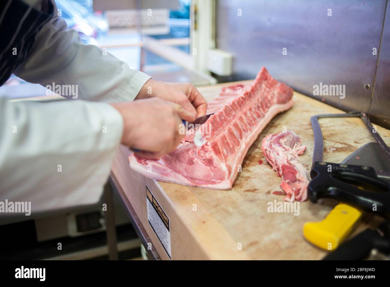 A butcher prepares high-welfarepork to sell in his butchers store Stock Photo